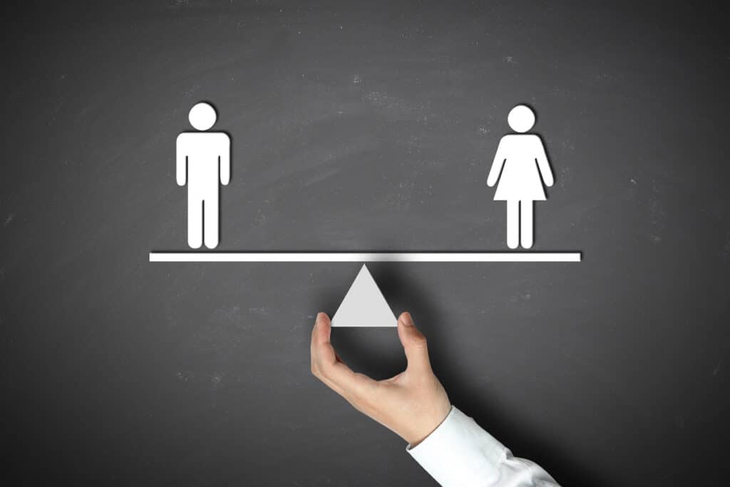 Égalité des sexes : homme et femme en équilibre parfait Icônes d'homme et de femme en équilibre sur une balance tenue par une main, symbolisant l'égalité des sexes.